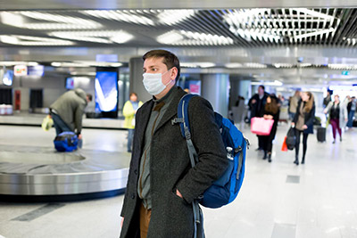 Image of masked business traveler in airport