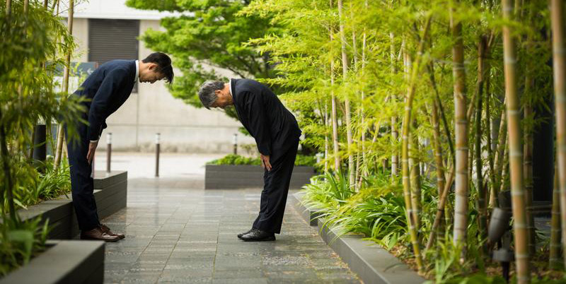 Two businessmen bowing courteously to each other in advance of a business meeting